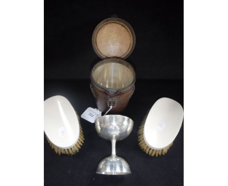 A SILVER PLATED DRINKING CUP in a fitted leather case and two ivory backed brushes