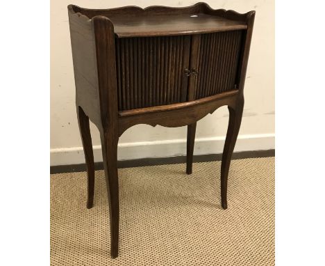 A French oak pot cupboard, the three quarter galleried top over two tambour doors and a shaped frieze on cabriole legs in the