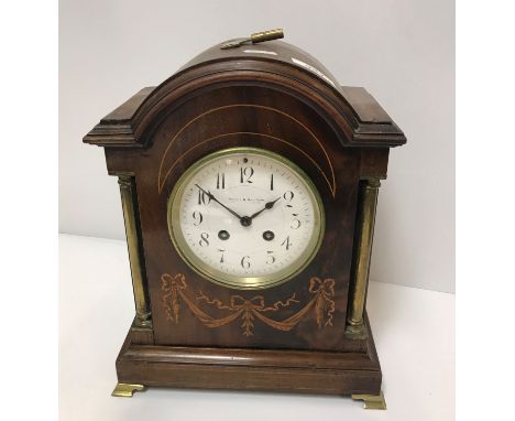 An Edwardian mahogany and inlaid dome top mantel clock of architectural form, with brass column decoration on ogee bracket fe