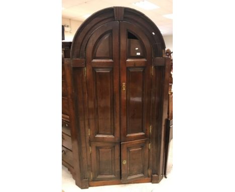 A George III oak free-standing barrel back corner cupboard, the dome top with moulded cornice above two arch fielded panelled