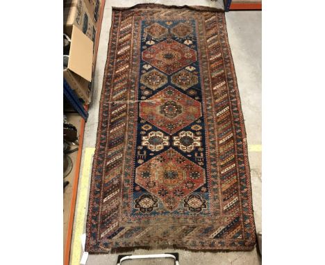 A Caucasian rug, the central panel set with repeating medallions on a blue ground with stylised flower head and animal decora