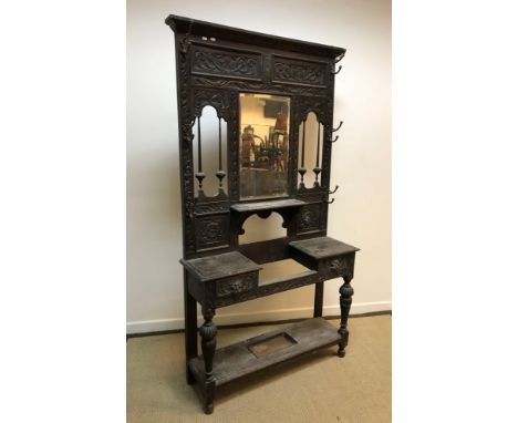 A late Victorian carved oak hall stand in the Gothic Revival taste, the mirrored back with small shelf and six coat hooks ove