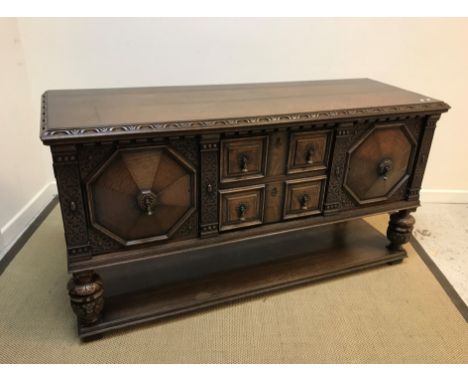 An early to mid 20th Century carved oak sideboard in the Elizabethan taste, the plain top with carved edge over two fielded p