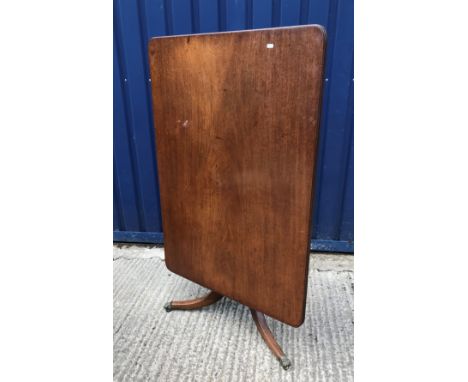 An early 19th Century mahogany tea table, the rounded rectangular snap top with reeded edge on turned and ringed centre pedes