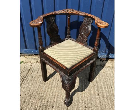 A 19th Century carved oak corner chair, the yoke back with mask decoration and dolphin carved splats interspersed by fluted a