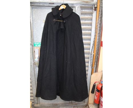 A large black woolen Cloak, possibly clerical, having mask lion button and chain fastening, label 'The House of Uarheems'.