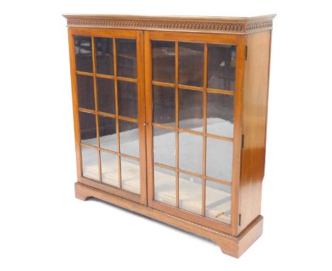 A 20thC mahogany bookcase, with a blind fret top above two astragal glazed doors, with arrangement of three shelves, on brack