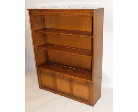 An Ercol light elm bookcase, with four shelf rack with two cupboard base, on stiles, 126cm high, 98cm wide, 30cm deep.