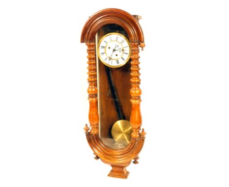 A late 19thC beech drop dial wall clock, with an arched top, on turned pilasters, and a shaped foot, with white Roman numeric