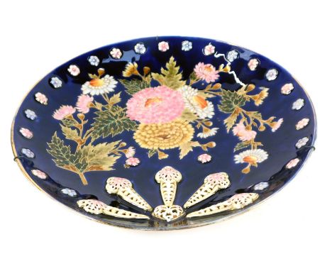 An early 20thC Zsolnay Pecs pottery charger, with reticulated and painted floral decoration, against a cobalt blue ground, pr