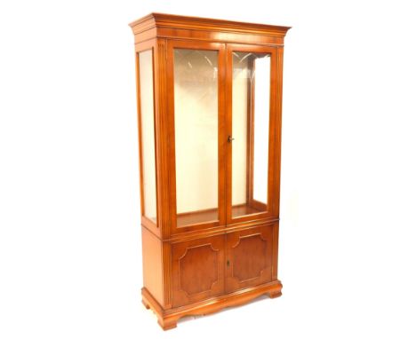 A modern cherry finish display cabinet, with a moulded cornice on reeded column supports, with moulded glass doors, two cupbo