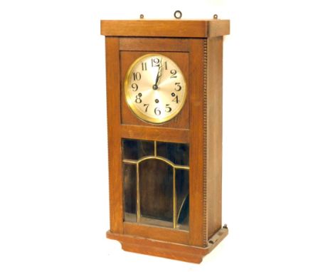 A 1950's oak cased wall clock, with a silvered numeric dial, eight day chiming movement, with beaded borders, and a glazed pa