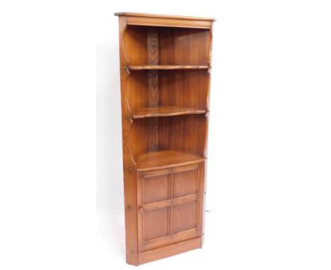 An Ercol light elm corner cabinet, with three tiered shelf section above single door, 183cm high, 70cm wide, 45cm deep.