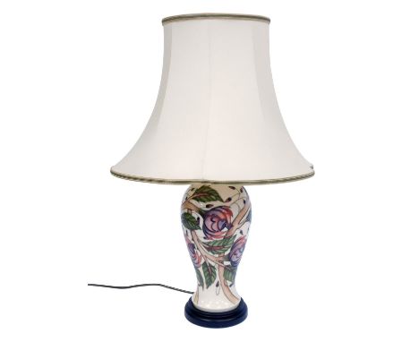 A Moorcroft table lamp, on a cream ground with pink and purple flowers, on ebonised base, with cream shade, 54cm high.