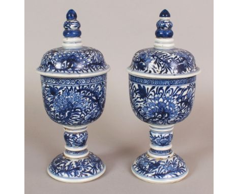 A PAIR OF CHINESE KANGXI STYLE BLUE & WHITE PORCELAIN STEM BOWLS & COVERS, each decorated with scrolling peony, 10in high.