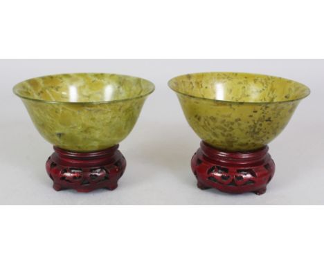 TWO 20TH CENTURY CHINESE MOTTLED GREEN JADE-LIKE BOWLS, with fitted wood stands and a fitted box, each bowl 3.9in wide & 1.75