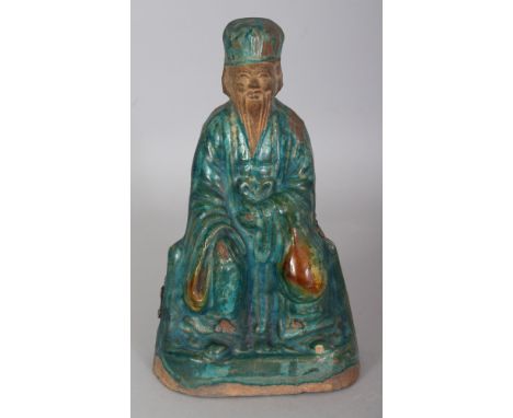 A CHINESE MING DYNASTY FAHUA GLAZED CERAMIC FIGURE OF A SEATED DIGNITARY, the mainly turquoise glaze containing areas of ochr