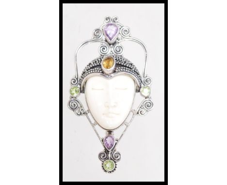 A contemporary unusual ring with a central oriental ceramic face including citrine and amethysts.
