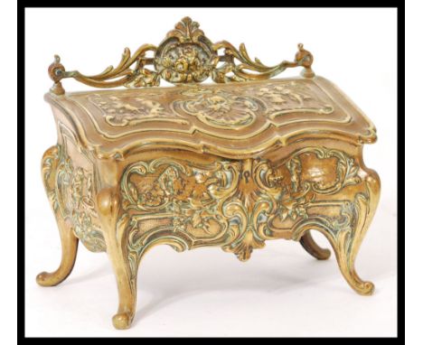 A 19th century brass desk inkwell modelled as a French commode decorated in relief with scroll work.