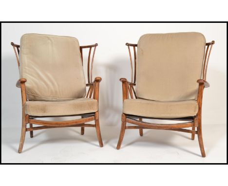 A pair of 20th century armchairs in the manner of Ercol. Each with loose cushions to seat and back rests. The back rests of l