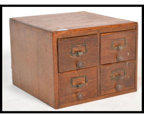 A vintage retro 20th century industrial office four section filing unit having brass name holder mounts with wooden knob hand