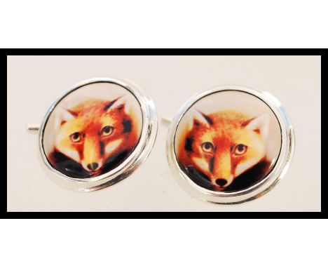 A pair of silver cufflinks with enamel panels featuring foxes. The cufflinks have a chain link fastening and are approximatel
