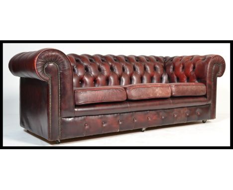 A 20th century antique style oxblood red leather Chesterfield sofa settee having buttoned back leather scrolled arms and back