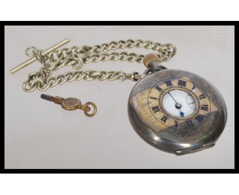 An early 20th century silver hallmarked London import pocket watch in a half hunter silver case. The white enamel face having
