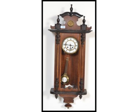 A vintage 20th century Vienna Regulator style mahogany cased wall clock having an arched pediment top. The white enamel face 