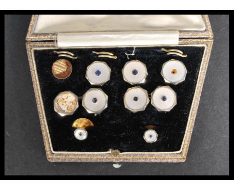 A cased set of dress cufflinks and studs,&nbsp; each mother-of-pearl link is centred with a small blue sapphire stone&nbsp; w