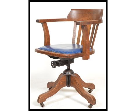 A vintage early 20th century Industrial oak office chair raised on a quadruped swivel base having a blue studded seat with ra