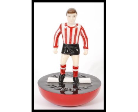 A Royal Doulton Subbuteo ceramic football figurine MCL 12 featuring a player in red and white stripped kit on black and red b