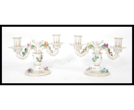 A pair of Dresden porcelain double sconce candelabras, each decorated with applied ceramic flowers and gilt motifs and raised