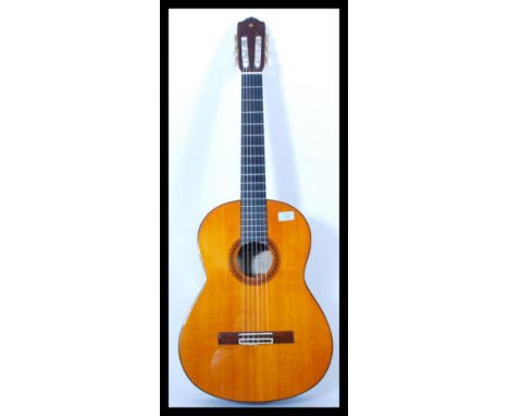 A vintage Yamaha six string acoustic guitar model CG 130 having a shaped hollow body with mother of pearl tuning pegs. Paper 