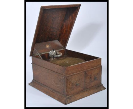 A vintage early 20th century oak cased gramophone record player by Beltona having a hinged lid with twin cupboards opening to