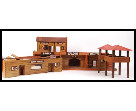 A vintage model wild west fort playset constructed from wood , board and plastic having a bank , saloon , stagecoach hire , j