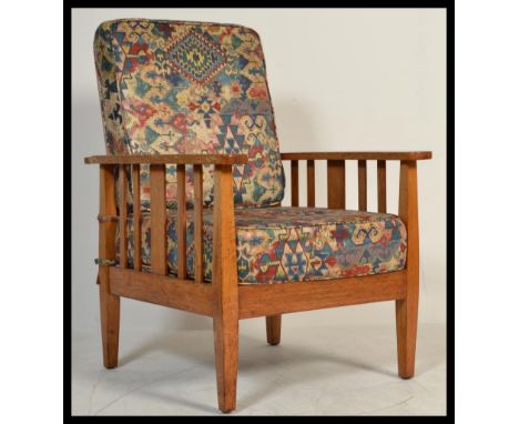 A 1930's Art Deco golden oak stick back armchair. Raised on squared legs with flat plank arm rests having upholstered seat an