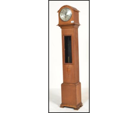 A vintage early 20th century oak cased granddaughter clock by Enfield. The silvered dial with chapter ring and faceted hands.