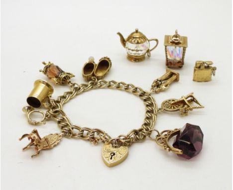 A 9ct gold double curb link charm bracelet with heart shaped clasp and eight attached charms with a further three loose to in