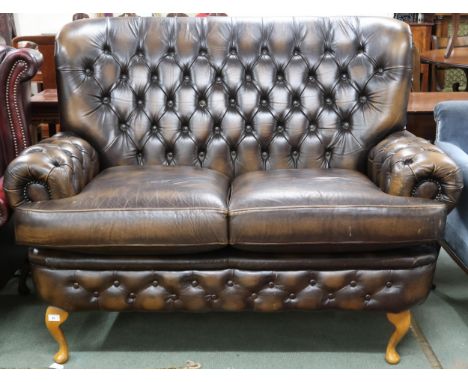 A 20th century brown leather button back Chesterfield style two seater settee on cabriole supports, 112cm high x 148cm wide x