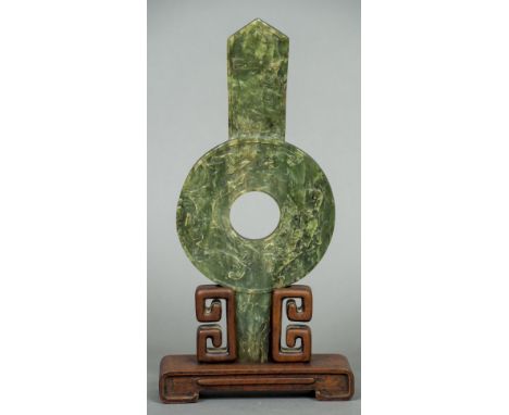 A Chinese jade bi diskOf unusual lugged form decorated with dragons chasing a pearl, mounted in a carved wooden display stand