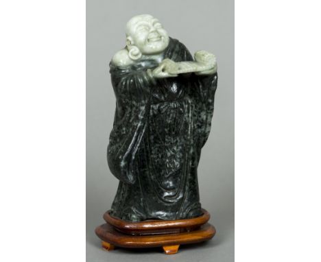 A carved jade figure of BuddhaModelled standing holding an open scroll, mounted on a wooden plinth base.  21 cm high.    COND