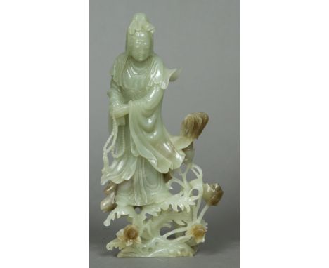 A Chinese carved jade figure of GuanyinModelled holding a string of beads standing amongst budding flowers.  22.5 cm high.   