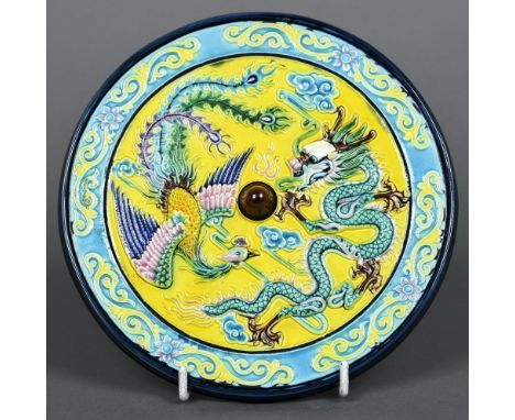 A Chinese porcelain roundelThe blue and yellow ground centred with a dragon and a phoenix, the underside with impressed seal 