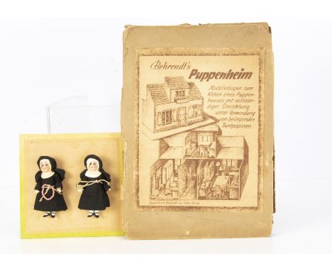 Two all-bisque nun dolls’ house dolls, with blue glass eyes, black habits and mounted on green edged card, probably of recent