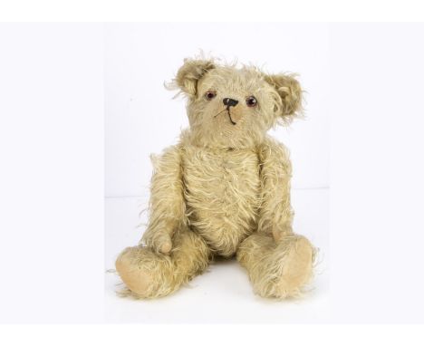 A 1920s French teddy bear, with long blonde mohair, clear and black glass eyes with remains of red painted backs, pronounced 