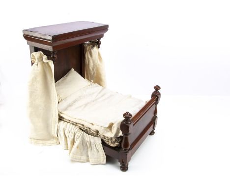 A 19th century doll’s half-tester bed, mahogany with turned posts and curtain rail end, wooden slats, original button mattres