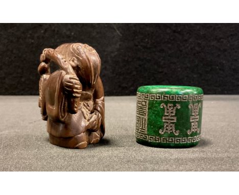 A carved wooden netsuke, as a bearded Elder, 5.2cm high,  a carved green stone Archers ring, possibly nephrite,2.9cm wide 