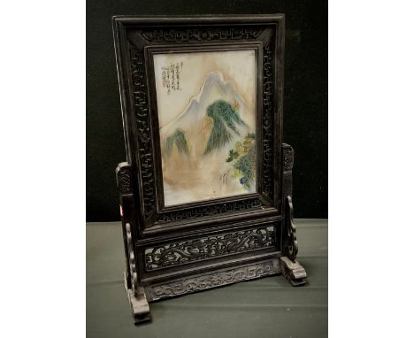 A Chinese porcelain and carved wooden table screen, Traditional mountain landscape, 66cm high, 46cm wide. 