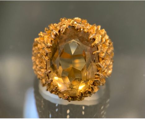 A citrine signet ring, volcanic effect textured mount surrounding a pale oval citrine, 9ct gold shank, size O, London 1975, 9